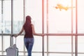 Traveler woman standing and hand holding luggage bag see the airplane at the airport glass window. Royalty Free Stock Photo