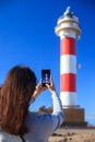 Traveler woman taking photo of lighthouse on beach on Canary Isl