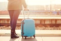 Traveler woman waiting at railway station. Travel by train. Girl standing with blue luggage suitcase in morning. Journey concept. Royalty Free Stock Photo