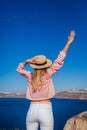 Traveler woman walking on Santorini island, Greece enjoying sea landscape. Girl enjoys Caldera view with arm raised Royalty Free Stock Photo