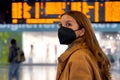 Traveler woman wearing a black protective mask KN95 FFP2 at the airport to protect from virus. Young woman with timetables