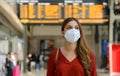 Traveler woman wearing KN95 FFP2 face mask at train station to protect from virus and smog. Young caucasian woman with timetables