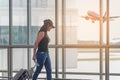 Traveler women plan and backpack see the airplane at the airport glass window, girl tourist hold bag and waiting near luggage in h Royalty Free Stock Photo