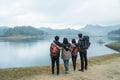 Travelers with backpacks overlooking enjoy lake view from meadow