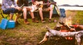 Travelers camping doing picnic and playing music in meadow field. Mountain and lake background. People and lifestyles concept. Royalty Free Stock Photo