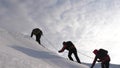 Travelers climb rope to their victory through snow uphill in a strong wind. tourists in winter work together as team