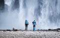 Travelers couple look at the Skogafoss waterfall. Travel and active life concept with team.