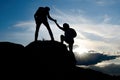 Travelers Hiking in the Mountains at Sunset. Man Helping Woman to Climb to the Top. Family Travel and Adventure. Royalty Free Stock Photo