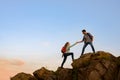 Travelers Hiking in the Mountains at Sunset. Man Helping Woman to Climb to the Top. Family Travel and Adventure. Royalty Free Stock Photo