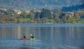 Travelers kayak towards shore and weekend houses hiding in trees changing colors Royalty Free Stock Photo