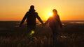 Travelers, a man and a woman with backpack go to edge of mountain in rays of dawn, raise their hands in air and enjoy Royalty Free Stock Photo