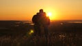 Travelers, a man and a woman with backpack go to edge of mountain in rays of dawn, raise their hands in air and enjoy Royalty Free Stock Photo