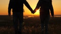 Travelers, a man and a woman with backpack go to edge of mountain in rays of dawn, raise their hands in air and enjoy Royalty Free Stock Photo