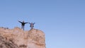 Travelers, a man and a woman with backpack go to edge of mountain in rays of dawn, raise their hands in air and enjoy Royalty Free Stock Photo