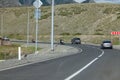 Travelers on motorcycles drive in a sharp turn on an asphalt road towards cars