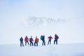 Travelers standing on snowy field in mountains.