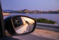 Traveling by car along beautiful coast at night. Reflection of sunset at side mirror. Royalty Free Stock Photo