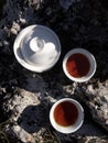 Traveling concept. Making black tea in white Chinese gaiwan and cups on big rock top view Royalty Free Stock Photo