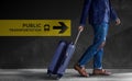 Traveling Concept. Traveler Walking with Luggage in the Airport, Public Transportation Sign on the Wall as background