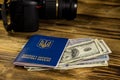 Traveling concept with ukrainian passport, dollars and modern photo camera on wooden desk Royalty Free Stock Photo