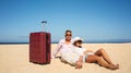 Traveling couple relaxing with suitcases at the beach on a sunny summer day, tired after looking for the good place for sunbathing Royalty Free Stock Photo