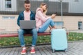 Traveling. Couple using laptop, waiting transport near airport Royalty Free Stock Photo