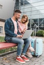 Traveling. Couple using laptop, waiting transport near airport Royalty Free Stock Photo