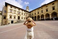 Traveling in Tuscany. Back view of tourist girl holding hat in Piazza Grande square in the historic town of Arezzo, Tuscany, Italy Royalty Free Stock Photo