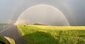 Traveling under a double rainbow car, along a highway along a field