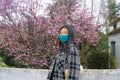 Traveling in virus times - young happy and beautiful Asian Korean woman in face mask against covid19 enjoying sakura blooming tree Royalty Free Stock Photo