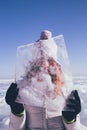 Traveling woman with block of ice gleaming in the sun. Winter tourism in Russia Baikal Lake