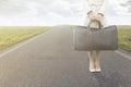 Traveling woman waits with her suitcase on the roadside