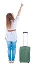 Traveling young woman with suitcas points at wall. Royalty Free Stock Photo
