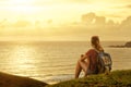 Traveller with backpack enjoying sunset listening to music on pe Royalty Free Stock Photo