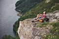 Traveller with backpack sitting on top of mountain enjoying view above the water surface. Traveling along mountains and Royalty Free Stock Photo