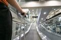 Traveller female holding suitcase on escalator at airport or transit flight with luggage on holiday traveling in elevator arriving Royalty Free Stock Photo