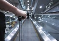 Traveller female holding suitcase on escalator at airport or transit flight with luggage on holiday traveling. Royalty Free Stock Photo