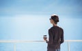 Traveller girl standing on ferry boat, looking at the sea and holding a coffee cup, travel and active lifestyle concept Royalty Free Stock Photo