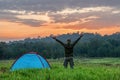 Traveler having camping with tent on grass field in morning of sunrise