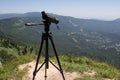 Traveller looking the nature from the high mountain with spotting scope, binoculars tripod