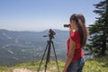 Traveller is looking the nature from the mountain with binoculars tripod and video camera
