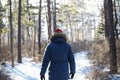 Traveller man in a blue winter jacket ad red cap in the woods. Sandy bay, Baikal lake, winter time