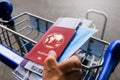 Traveller with passport, mask and boarding pass in, holding on to airport trolley Royalty Free Stock Photo