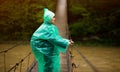 Traveller senior beautiful woman in blue rain jacket cross river by hinged bridge in forest, enjoying silence Royalty Free Stock Photo