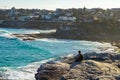 Traveller sitting on the edge of rock cliff, looking to the blue