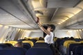 Traveller woman open overhead locker on airplane