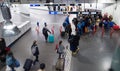 Travellers walk through train station carrying suitcases