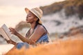 Travelling alone, dont need no baggage. a beautiful young woman relaxing with a book at the beach. Royalty Free Stock Photo