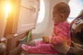 Travelling with infant. Mother and baby sitting together in airplane near the window in sunny day