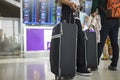 Travelling suitcase against flight information board on background. Concept of travel by airplane